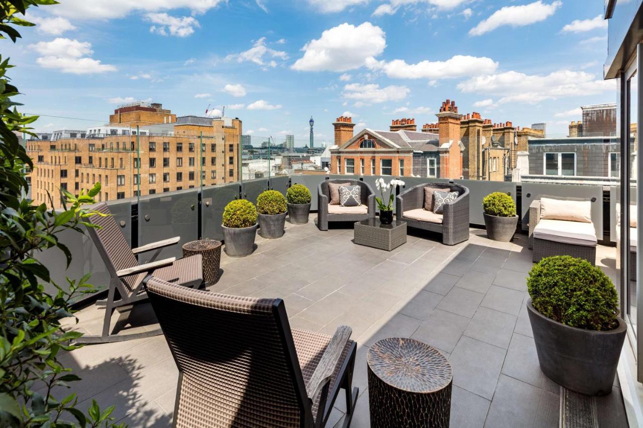 The May Fair, A Radisson Collection Hotel, Mayfair Londra Esterno foto The photo depicts a spacious outdoor terrace or balcony. It features modern outdoor furniture, including comfortable seating arrangements with chairs and cushions. There are several planters with neatly trimmed greenery, adding a touch of nature to t