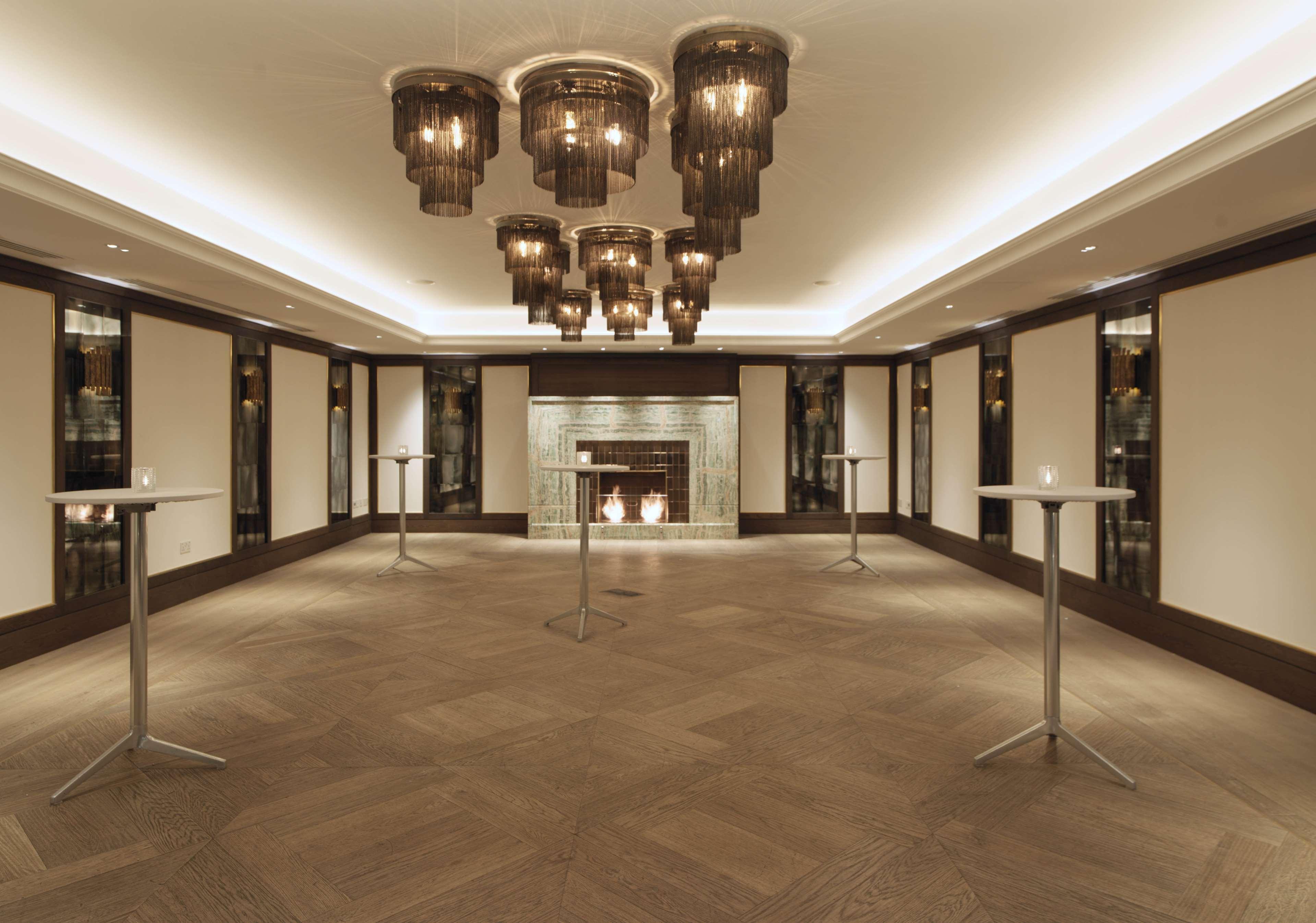 The May Fair, A Radisson Collection Hotel, Mayfair Londra Esterno foto The photo showcases an elegant indoor space, likely designed for events or gatherings. The room features a sophisticated lighting arrangement with several modern pendant chandeliers hanging from the ceiling. There are minimalistic tall tables scatter