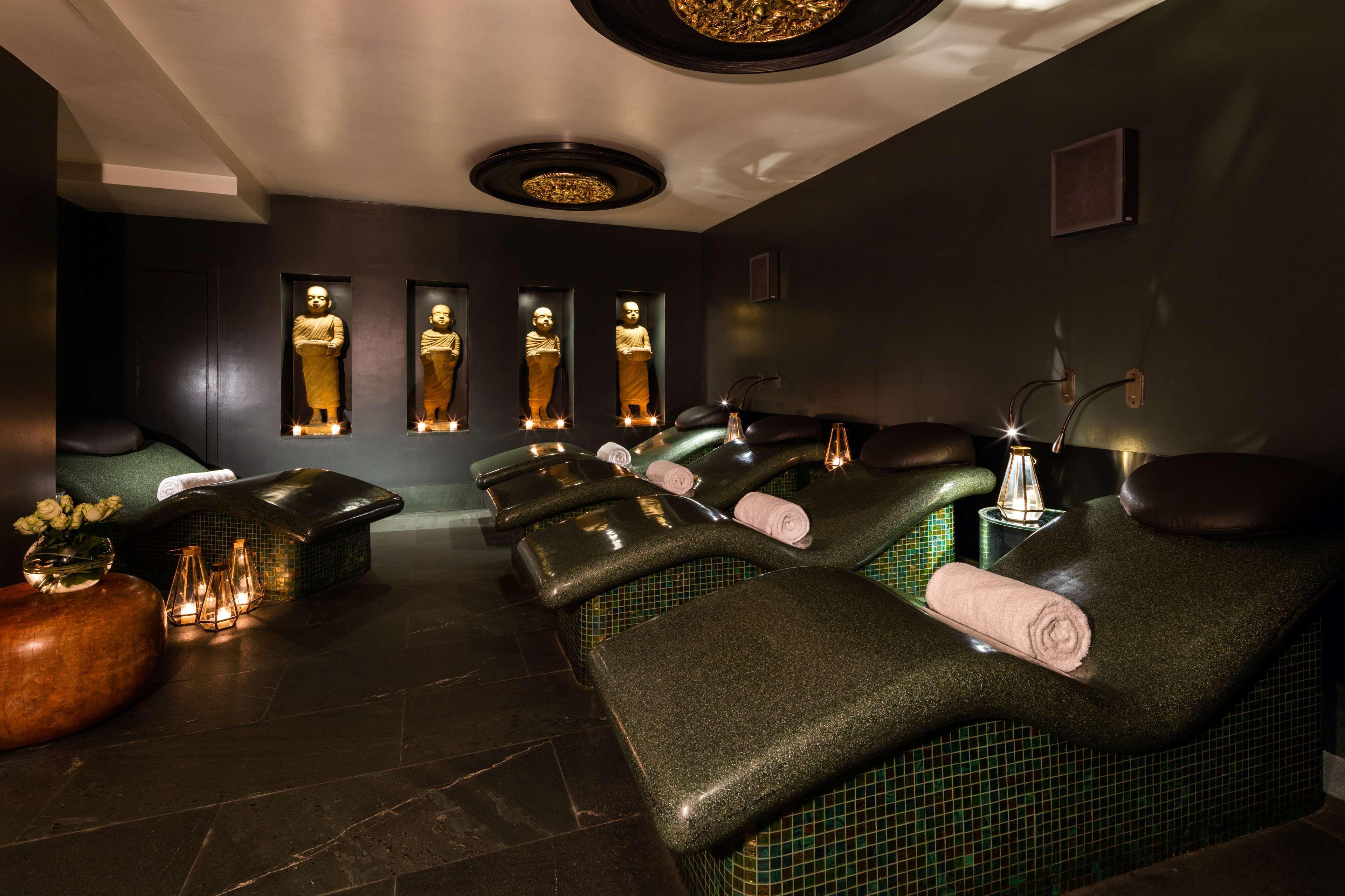 The May Fair, A Radisson Collection Hotel, Mayfair Londra Esterno foto The photo shows a tranquil spa environment. It features lounge chairs with curved backs, designed for relaxation, positioned in a dimly lit room. The walls are decorated in dark tones, providing a calming atmosphere. There are illuminated statues or 