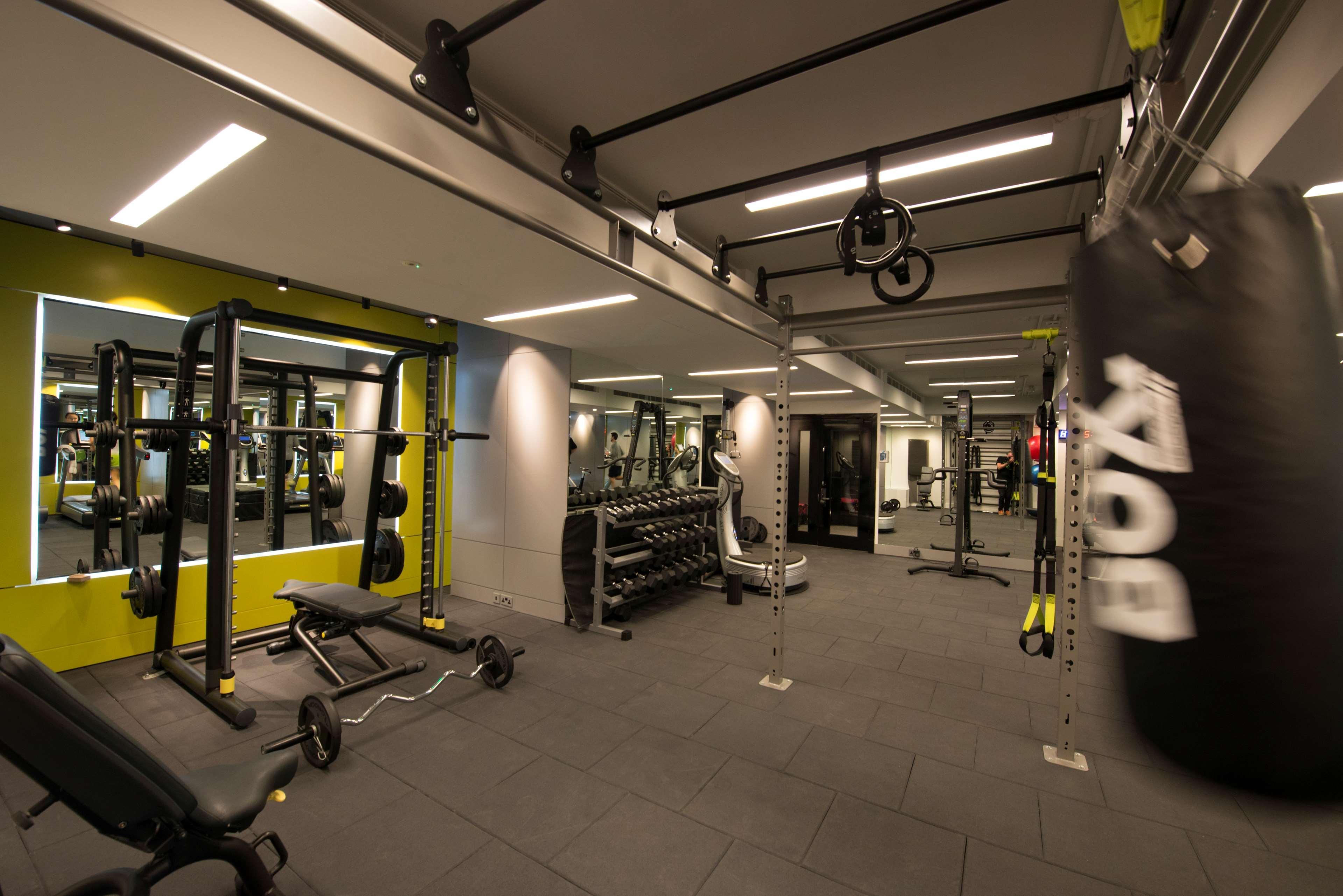 The May Fair, A Radisson Collection Hotel, Mayfair Londra Esterno foto The photo shows a modern gym interior. There are various fitness equipment pieces, including free weights, benches, and a multi-functional weight rack. The lighting is bright, with a mix of ceiling lights and mirrors on the walls that enhance the spa