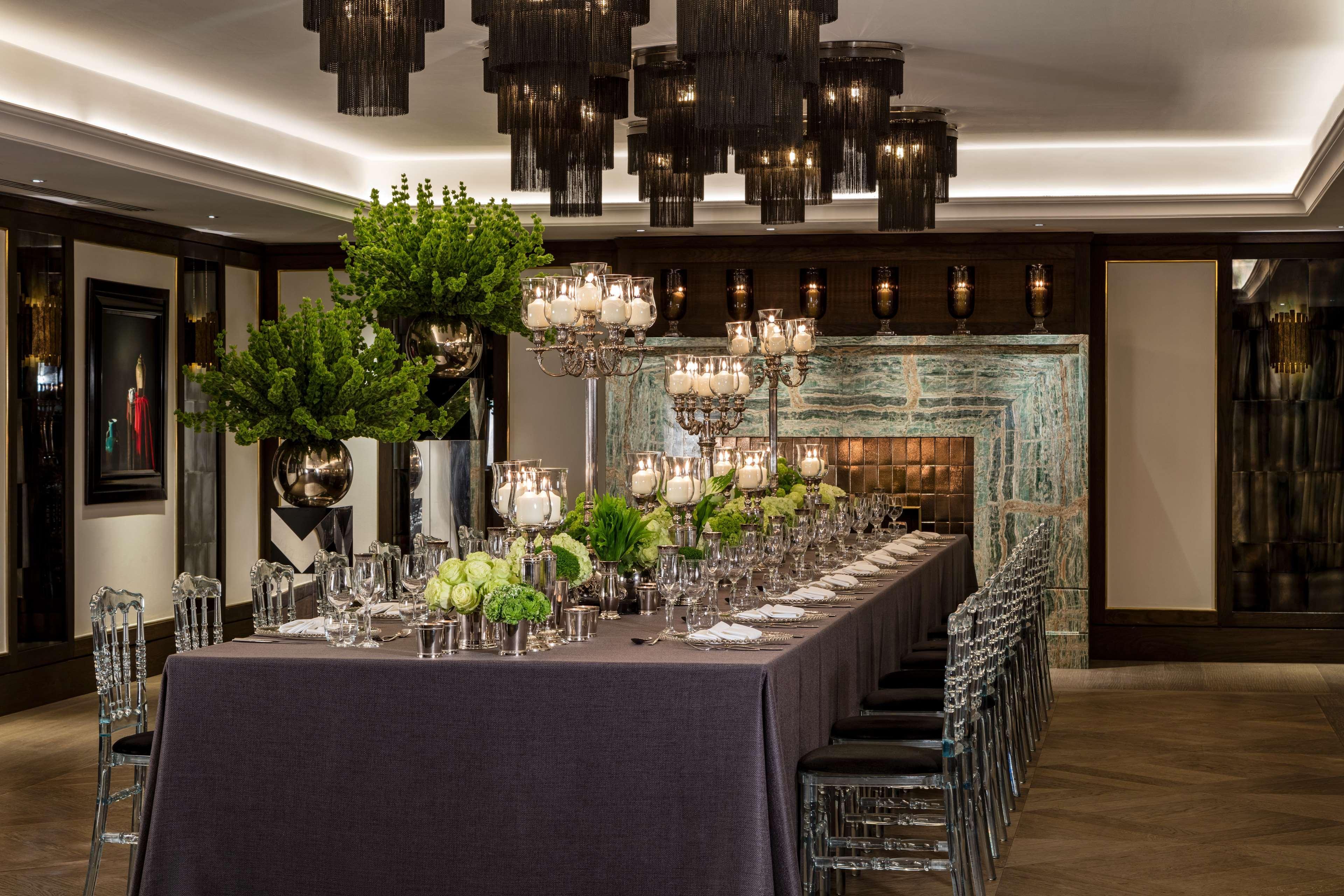 The May Fair, A Radisson Collection Hotel, Mayfair Londra Esterno foto The photo shows a sophisticated dining setting. A long table is elegantly arranged with a dark tablecloth and decorative centerpieces that include lush greenery and ornate candle holders. The table is set with glassware and tableware, indicating it i