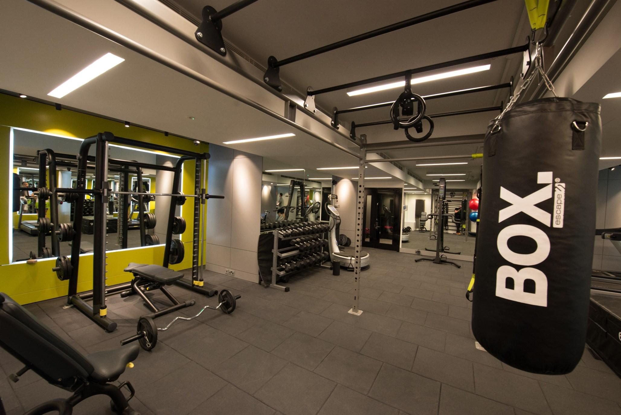 The May Fair, A Radisson Collection Hotel, Mayfair Londra Esterno foto The photo shows a modern gym interior. On the left, there is a weightlifting area with various equipment, including a set of dumbbells on a rack and a bench. In the center, there are resistance training apparatus and functional training tools. Hangin