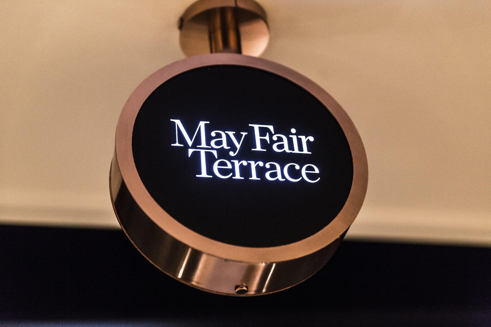 The May Fair, A Radisson Collection Hotel, Mayfair Londra Esterno foto The image shows a round sign with the text "May Fair Terrace" displayed in a stylish font. The sign is likely illuminated and mounted on a wall or ceiling, featuring a sleek design with a dark background and a metallic border, giving it a modern aest