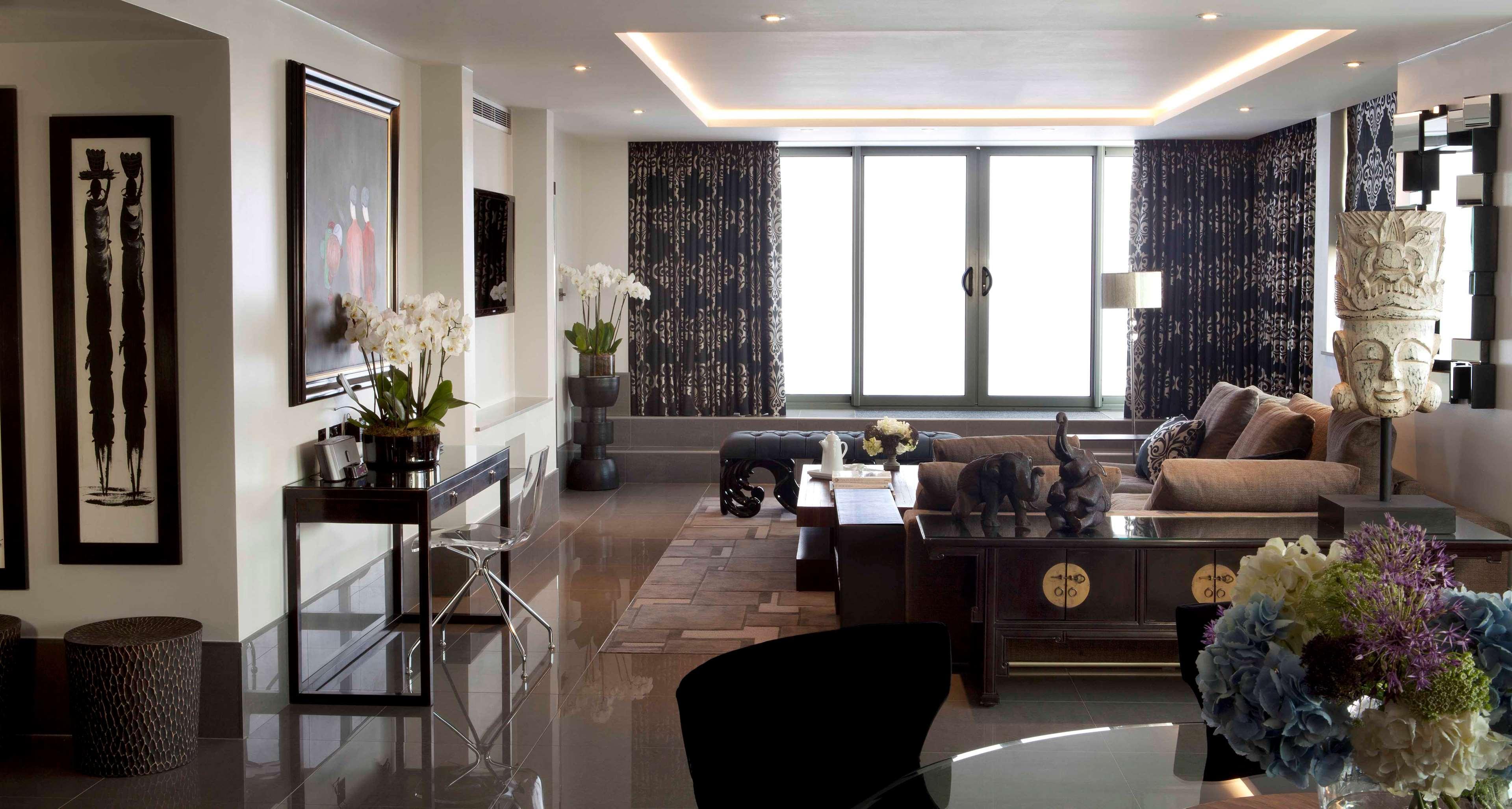 The May Fair, A Radisson Collection Hotel, Mayfair Londra Esterno foto The photo depicts an elegantly designed interior space, likely a living room. It features:

- A large window with modern curtains that allow natural light to filter in.
- A contemporary sofa, complemented by decorative pillows, situated around a coff