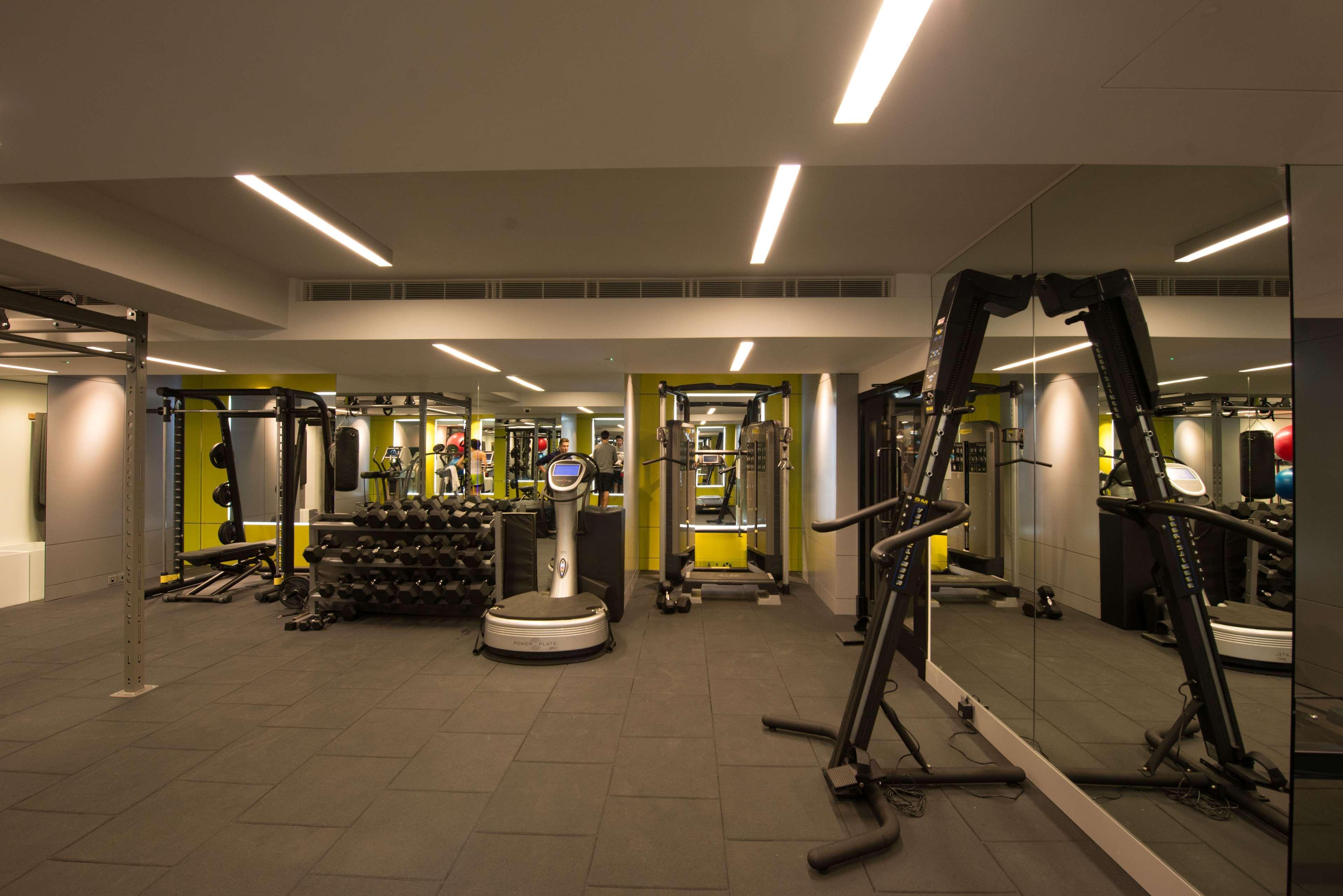 The May Fair, A Radisson Collection Hotel, Mayfair Londra Esterno foto The photo shows the interior of a gym. It features various exercise equipment, including weight machines, free weights, and a multi-purpose fitness machine. The gym has a modern design with yellow and gray accents, and it is well-lit with overhead li